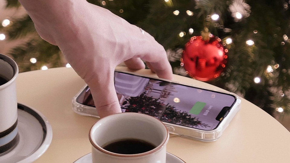 Using the charging function, a cell phone is placed on top of the product. There is a coffee cup next to it, showing it being used like a table.